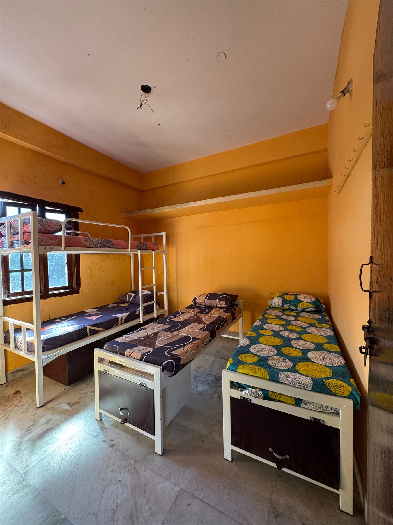 Boys hostel room with single bed beside a window