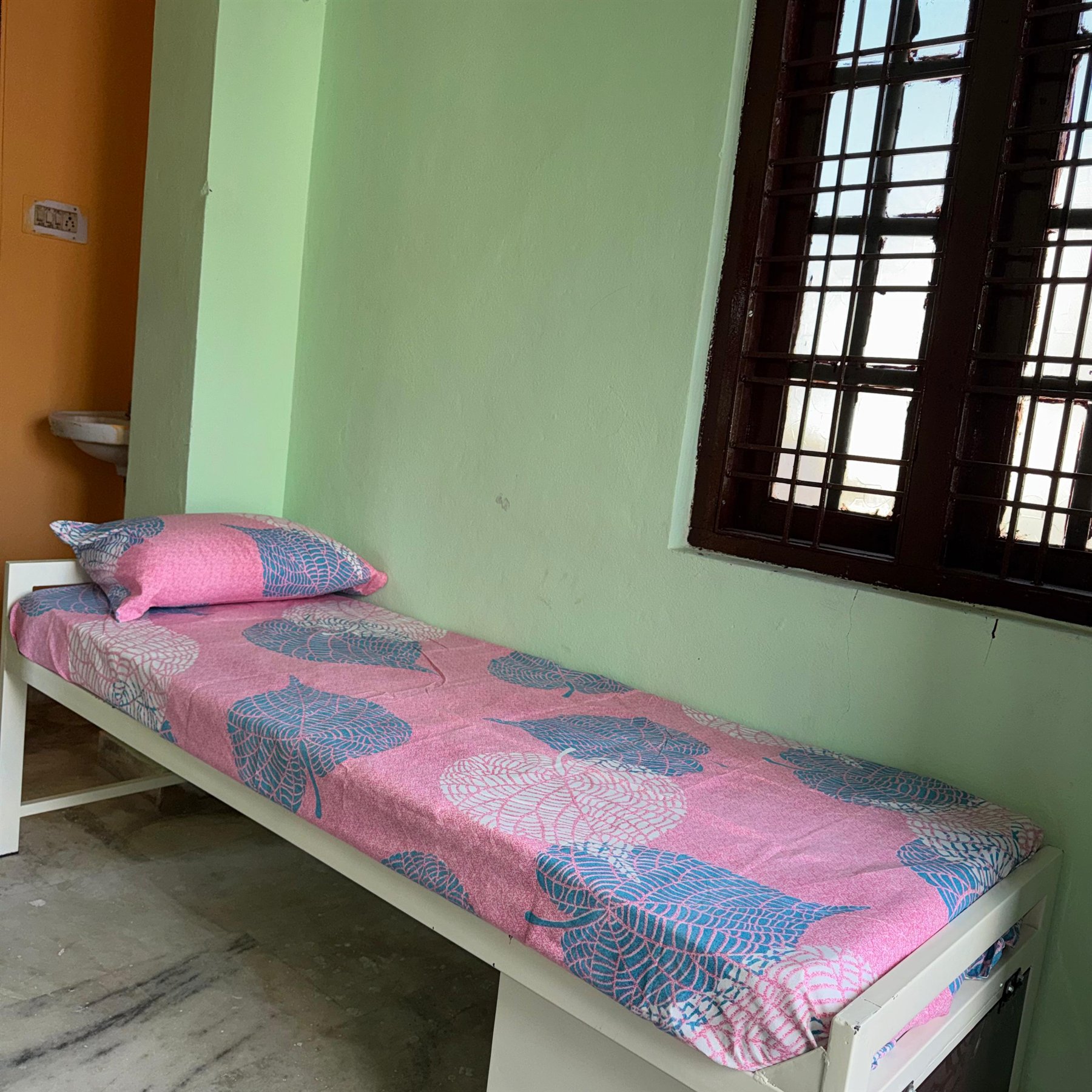 Boys hostel single bed with window and wash basin view